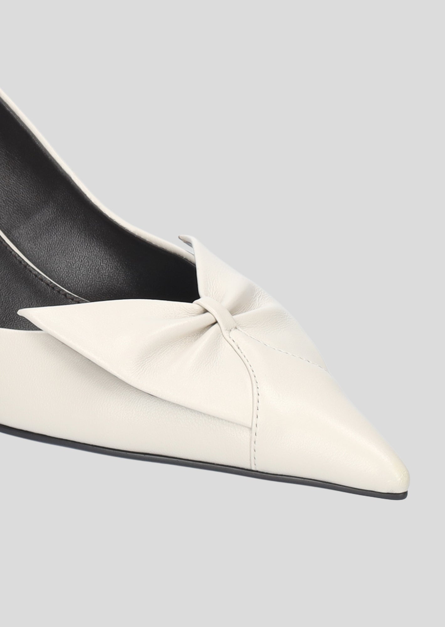 Vista lateral de los zapatos de salón de piel para mujer Manuela Pumps 50 en color Ecru con punta afilada, lazo de piel y tacón tipo embudo de Lola Cruz.
