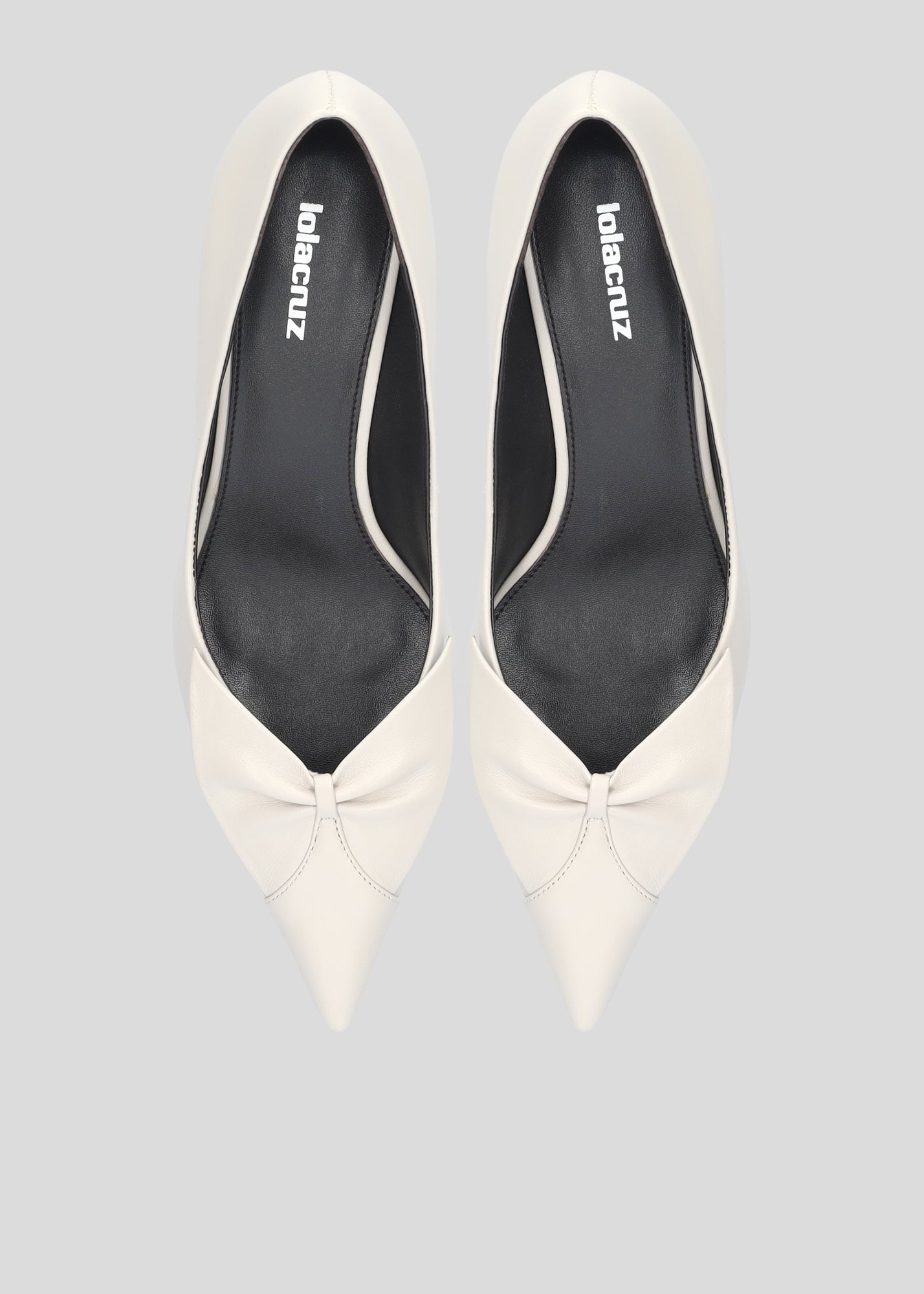 Vista lateral de los zapatos de salón de piel para mujer Manuela Pumps 50 en color Ecru con punta afilada, lazo de piel y tacón tipo embudo de Lola Cruz.